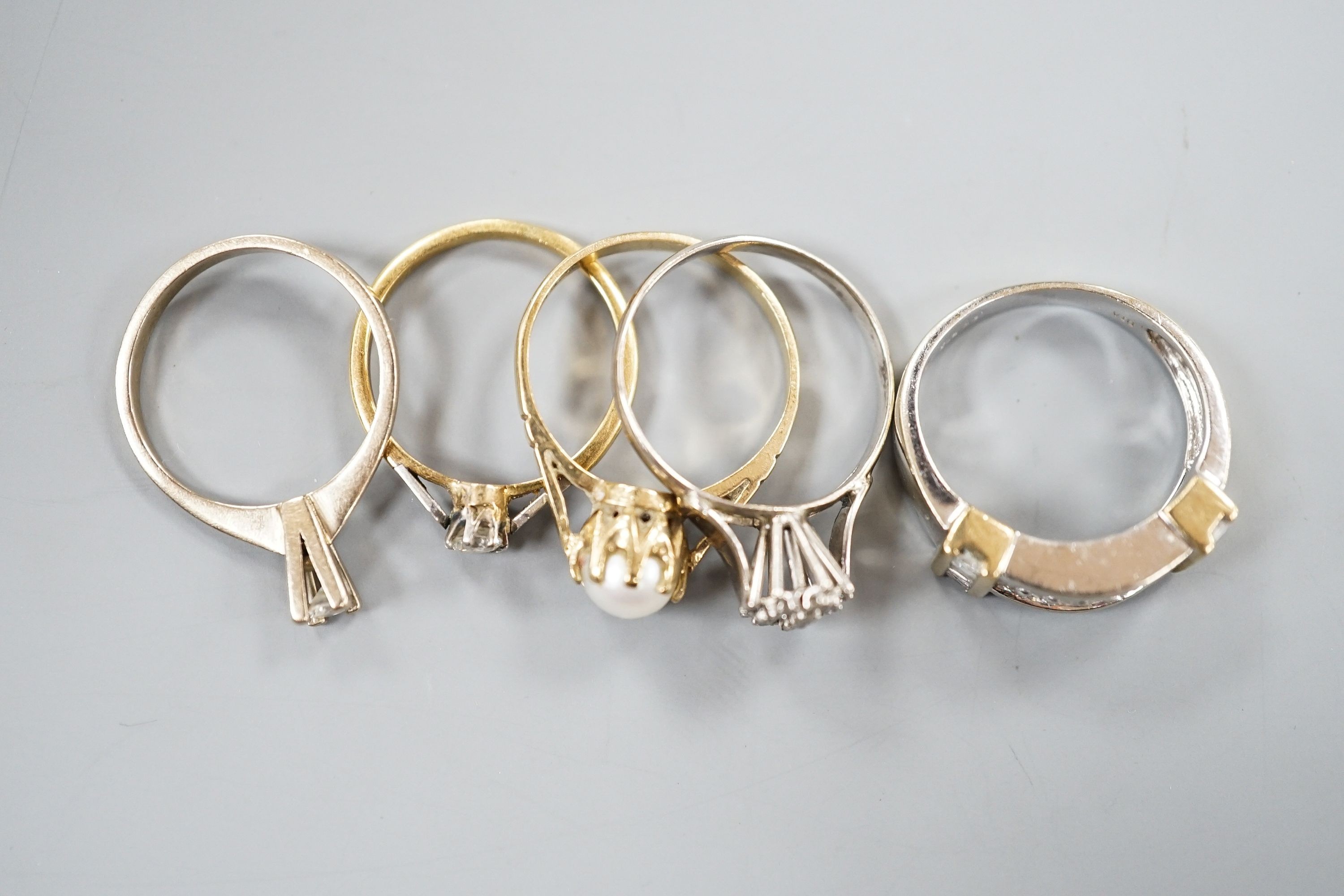 A 750 white metal and solitaire diamond ring, size K, gross 2 grams, two other yellow or white metal diamond set rings, gross 3.4 grams and two 9ct and gem set rings including cultured pearl, gross 6.3 grams.